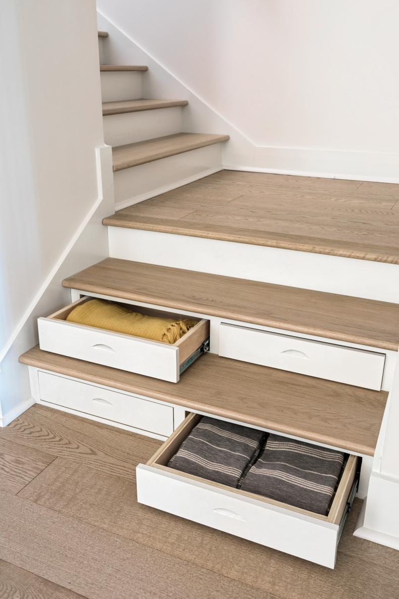 The first two steps of the stairs have clever drawers that offer storage for items used for the kitchen and great room, like linens, extra blankets, decorative pillows and gloves. This is one of the smart living features integrated in this impressive home.