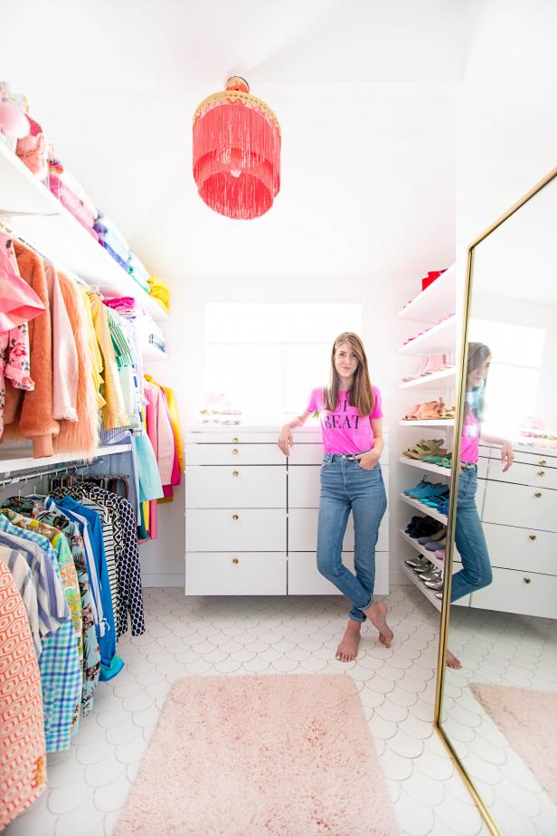 Kelly Mindell leans against a white dresser in her rainbow-themed closet.