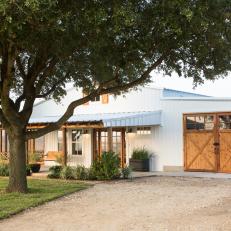 White Farmhouse Exterior and Garage with Brown Barn-Style Garage Doors
