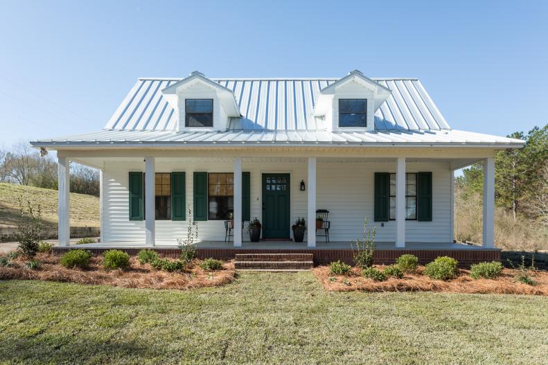 The exterior now features a metal roof, landscaping around the whole house, and new, chunky wood columns to replace the old posts.