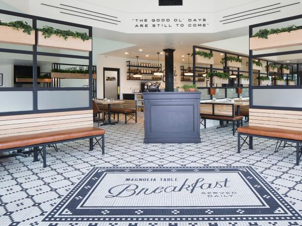 Magnolia Table restaurant entry and waiting area with black and white tile, wood benches, and sign: THE GOOD OL DAYS ARE STILL TO COME. #magnoliatable #fixerupper #joannagaines #restaurant