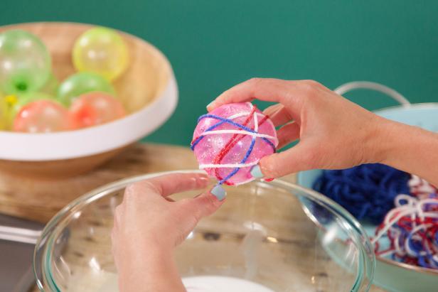 Wrap the glue-coated yarn around the water balloon in all different directions.