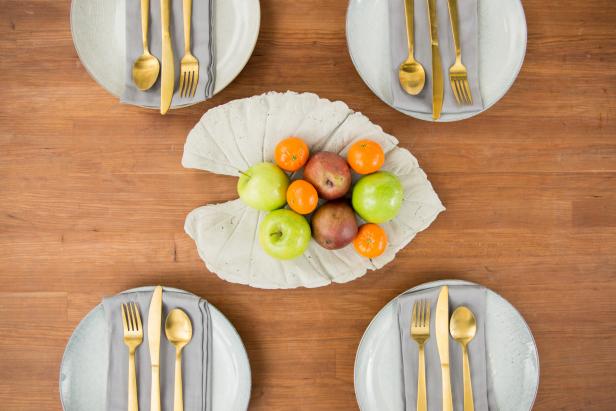 A DIY concrete leaf acts as the perfect fruit bowl for this modern table setting.