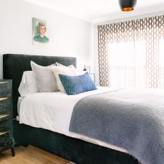 Black Bed Frame and Headboard Covered with White Bed Linens, Gray Throw and Mix of Pillows