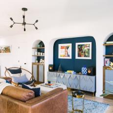 Bright Contemporary Living Room With Navy Accent Wall, Leather Sofa and Blue Accents 