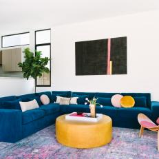 Modern Living Room With Blue Sectional Sofa And Pink Midcentury Modern Side Chair