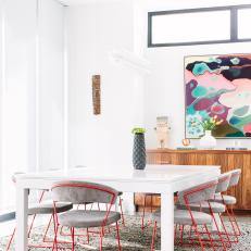 Modern White Dining Room With Orange Metal Dining Chairs And Colorful Modern Art 