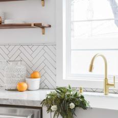 Farmhouse Sink and Herringbone-Pattern Backsplash in White Kitchen