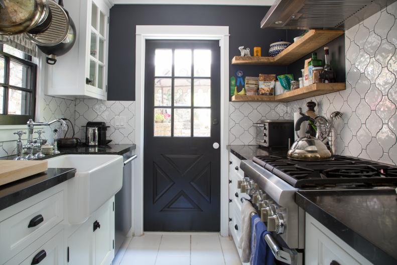 A galley kitchen that features white cabinet and black countertops. 