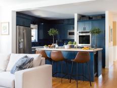 The navy kitchen island is lined with leather barstools.