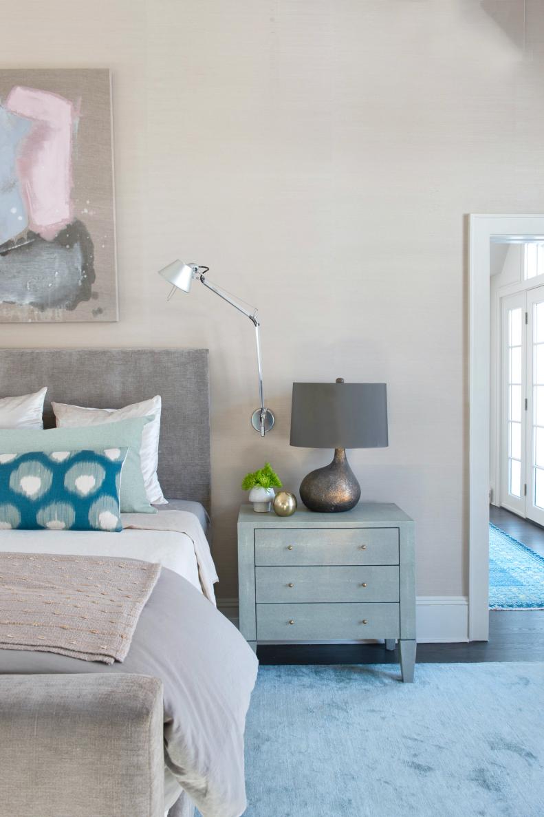 A bedroom that features a gray upholstered headboard and nightstand. 