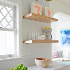 Modern White Kitchen Detail With Gold Wall Sconce And Floating Shelves With White Glass Tile