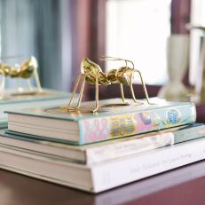 Stack of Books Topped With Golden Ant Sculpture