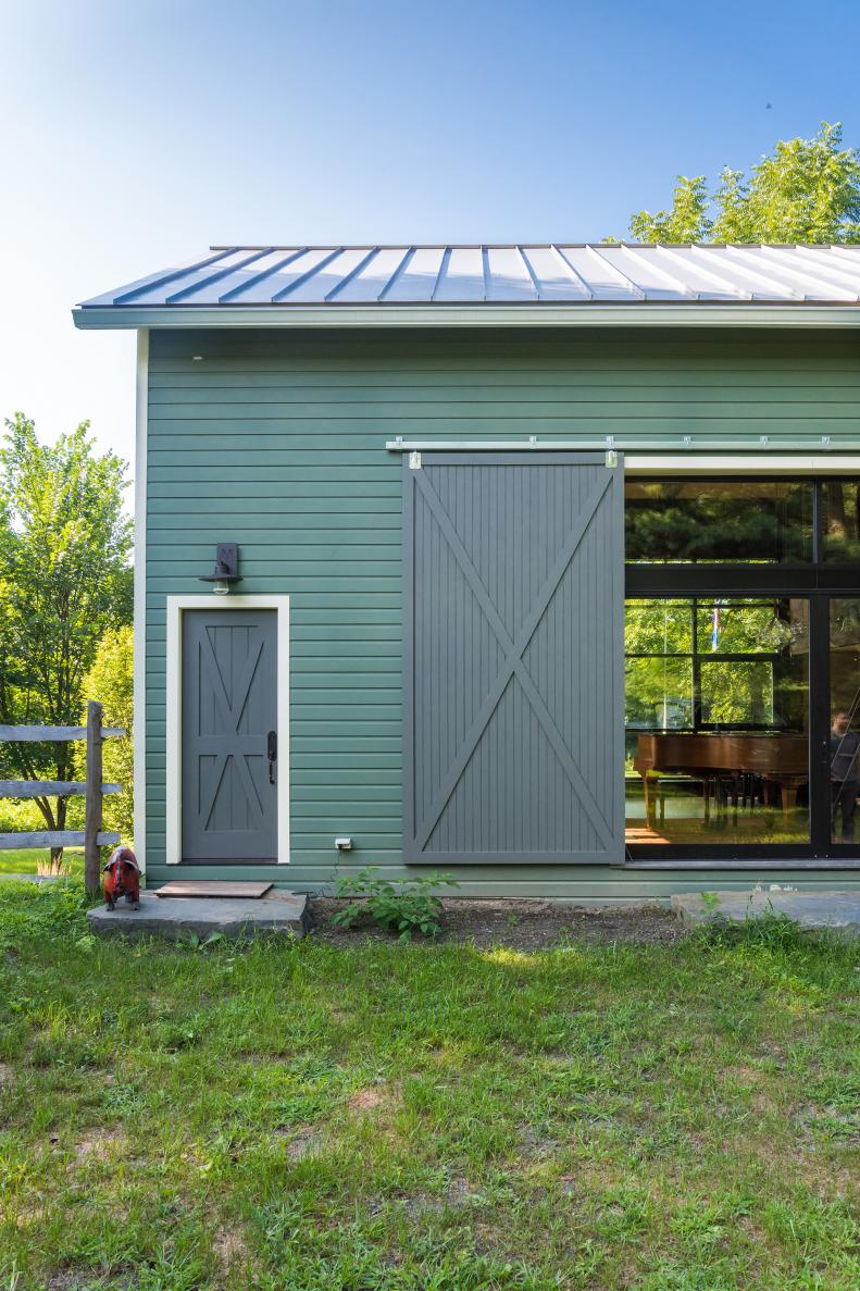 Green Barn Has Large Sliding Door That Covers Windows