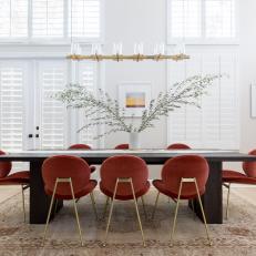 Modern White Dining Room With Coral Red Upholstered Chairs And Gold Accents
