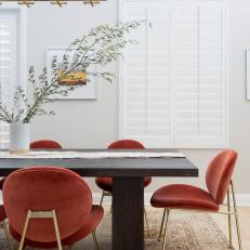 Modern White Dining Room With Red Upholstered Dining Chairs And Gold Accents