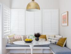 White Breakfast Nook With Gray Banquette And Gold Accents