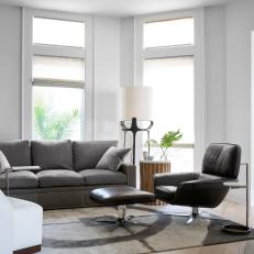 Contemporary Living Room With White Walls And Dark Gray Sofa And Black Chair With Ottoman