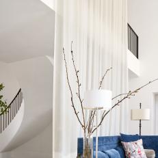 Modern White Living Room With Double Height Ceiling And Blue Sofa