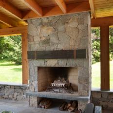 Outdoor Covered Patio Detail With Exposed Beams And Rafters And Stone Fireplace