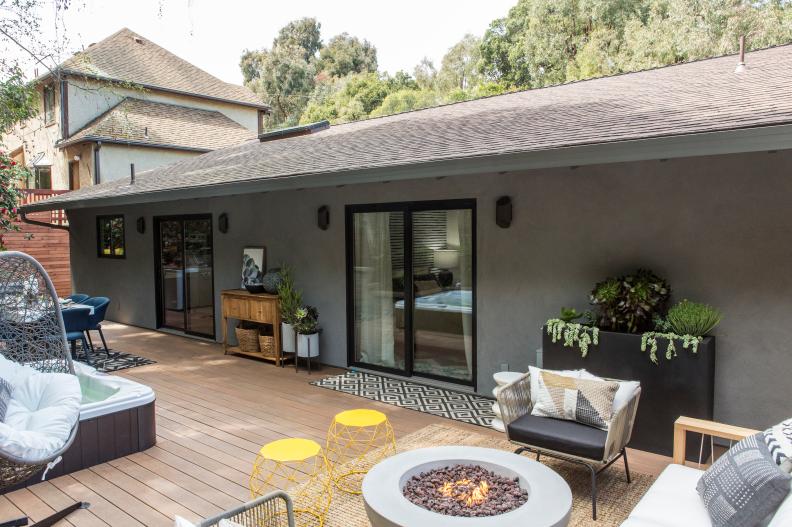 Drew Scott’s renovated backyard patio features en extended deck, a hot tub, firepit area and dining area, as seen on Brother vs Brother. (Before 0008).