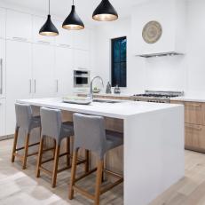 Modern White Kitchen With Panel Refrigerator And Work Island With Pendant Lights
