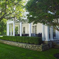 Classic White Porch With Outdoor Seating And Traditional Landscaping