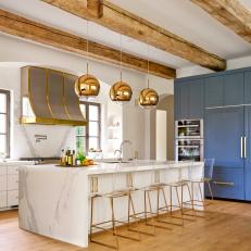 Bright Contemporary Kitchen Featuring Long Marble Island and Metallic Gold Accents