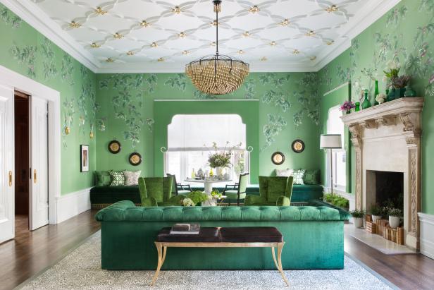 This elegant and eclectic living room features hand painted emerald green wallpaper, white and gold plaster detailed ceiling with gold chandelier, luxuriously upholstered sofas and chairs, and antique accessories throughout.