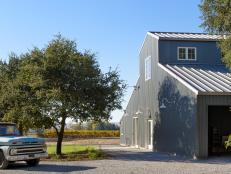 A view of the metal barn, vintage truck and vineyards in the rear. 