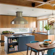 Open Concept Kitchen And Dining Room With Wood Cabinets And Blue Painted Word Island With Metal Vent Hood