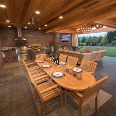 Outdoor Covered Living And Dining Room With Exposed Brick And Wood Beam Ceiling