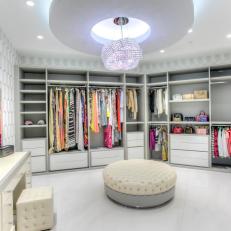 Boutique-Style Closet With Sparkling Chandelier, Tufted Ottoman