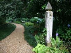 A charming pea gravel path is announced with a pair of vintage wooden posts. This Atlanta gardener's secret to gardening in a steamy Southern climate: doing your work first thing in the morning before things get too hot.
