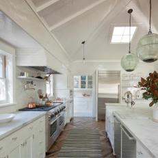 Large White Kitchen With Long Marble Countertop Island and Plank Board Vaulted Ceiling 