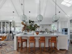 Open, Transitional Dine-In Kitchen With Leather Bar Chairs, Long Pendant Lights and Large Island