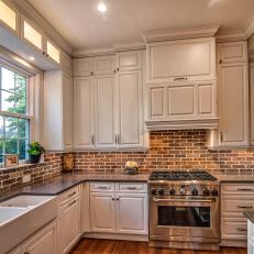 Contemporary Kitchen With White Cabinets And Brick Backsplash And Gray Countertops