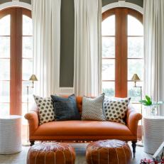 Traditional Sitting Area With Orange Loveseat And Leather Ottomans