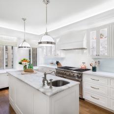 Traditional All White Kitchen With Glass Front Cabinets And Marble Work Island With Sink