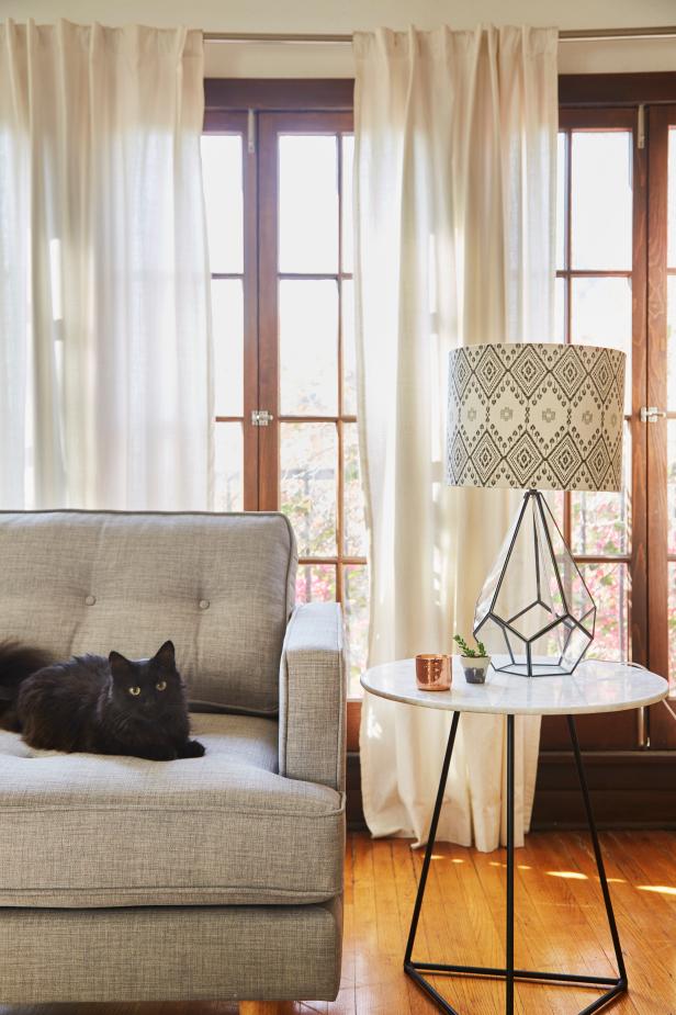 Everything about Nikia’s style is effortless — a casual elegance that the designers worked hard to translate into her home. Small touches, like the evolving layers of geometric pattern that go from the table legs to the lamp base to the lamp shade create a subtle but palpable mix of simplicity and sophistication. On the couch, “M” — a lucky black cat named for the letter formed by the shape of his head and ears — sits across the room from the portrait that he didn’t model for, but could have. 