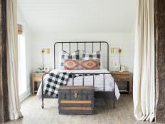 “We wanted to turn an old barn into a modern farmhouse for my client to host friends and family,” says designer Sarah Moore of Sarah Catherine Design. “In this bedroom, we countered the white shiplap walls with some bolder accents like an iron bed, bamboo shades, vintage chest and lots of buffalo check on the bed. I love how the bright walls and natural light coordinate with some of the more rustic features in this space to give it make it feel like a modern farmhouse cabin.”