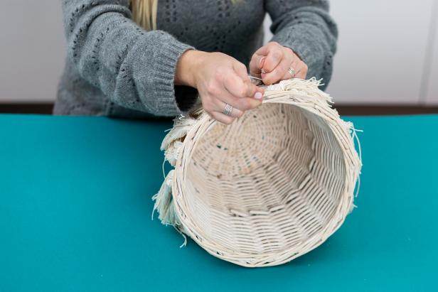Thread needle with a long piece of twine, and weave through the top of the basket. Tie a knot to keep it secure. Add two tassels onto the needle at a time, and attach to the basket until you’re finished.