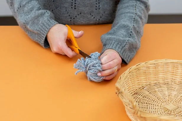 Make a pom-pom by wrapping thick yarn around four fingers 50 times. Loop a separate strand through the middle, tie tightly and cut the loops open. Trim.