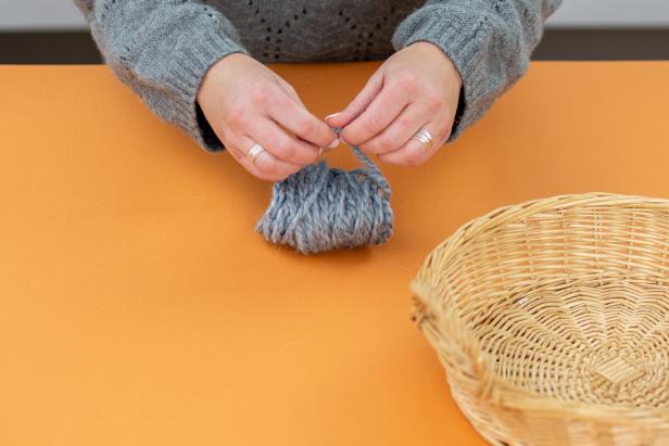 Make a pom-pom by wrapping thick yarn around four fingers 50 times. Loop a separate strand through the middle, tie tightly and cut the loops open. Trim.