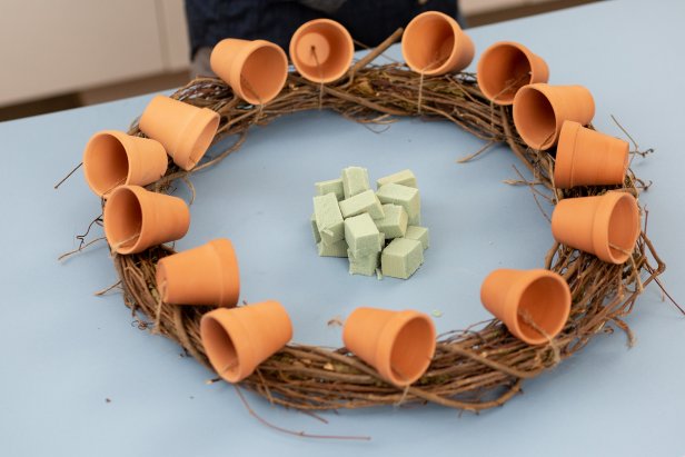 Cut floral foam into cubes small enough to fit inside the pots. Attach to the inside of the pot with hot glue. Attach two cubes to each pot if necessary.