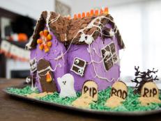 A Purple Gingerbread House With a Ghost and Headstones