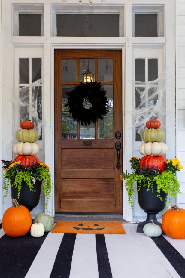 Two Planters Filled With Stacked Pumpkins Flanking a Door