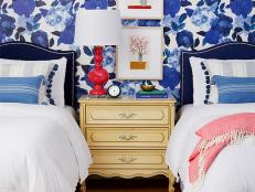 Place an antique, yellowish cream nightstand against an accent wall of giant blue blooms and suddenly it all feels of-the-moment. Navy headboards create more chic contrast so nothing looks matchy-matchy. The cherry on top: a lamp in a spunky hue.
