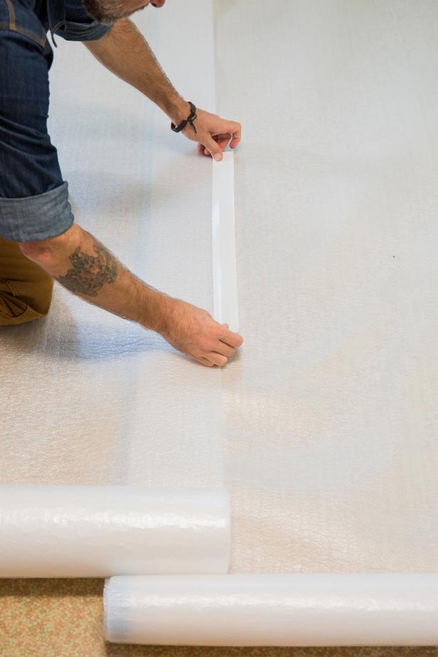 Directly onto the subfloor, lay down a layer of plastic sheeting to create a moisture barrier. Overlap the plastic sheeting by six inches.