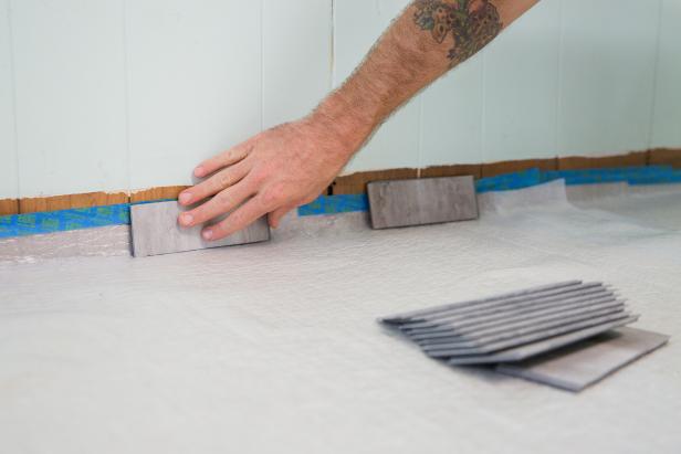 Use small sections of planks as spacers to hold the flooring away from the wall about 1/4 inch. The spacers help allow for expansion around the perimeter of the floor.